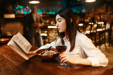 Woman reading a book at wooden bar counter