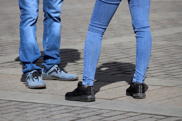 Couple wearing jeans stands on the street. Male and female legs on sidewalk, denim fashion