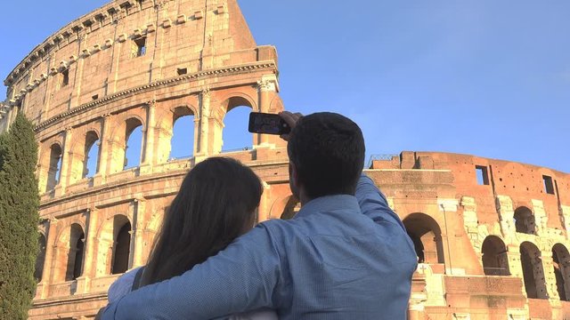 Man and woman embrace and take picture to Colosseum in rome