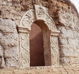 carved stone door against adobe brick wall