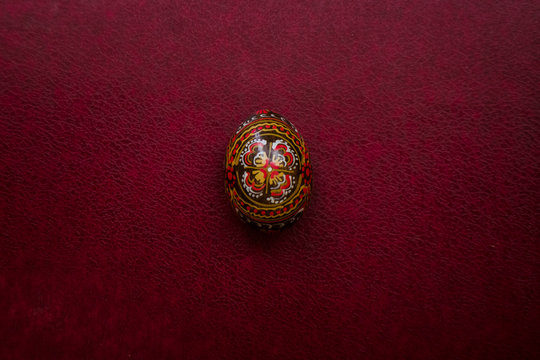 Easter black egg  with a handmade pattern. Closeup view on empty magenta leather background, place for your text. Minimal composition. Easter wallpaper concept.