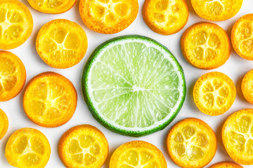 One lime slice surrounded by kumquat slices - 259437146