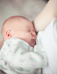 cute newborn baby sleeps in the arms of his mother.