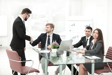 handshake business colleagues near the office desktop