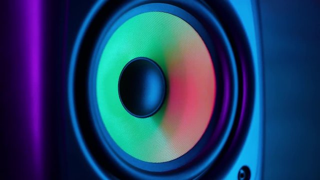 Macro close up of vibrating loud sound speaker in colorful neon lighting