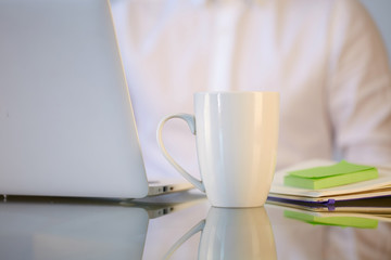 White ceramic mug on the work desktop of businessman.