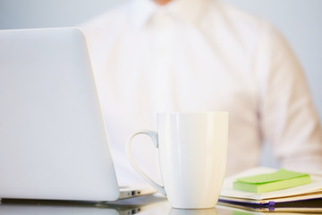 White ceramic mug on the work table of businessman.