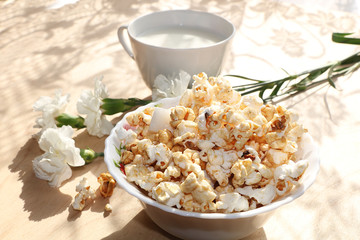 A mug of milk and a cup with popcorn on a sunny table, a bouquet of spring flowers for mood, diet food and a healthy lifestyle in the village, the perfect morning in the village