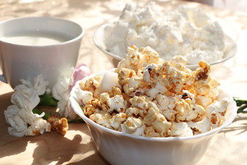 A mug of milk and a cup with popcorn on a sunny table, a bouquet of spring flowers for mood, diet food and a healthy lifestyle in the village, the perfect morning in the village