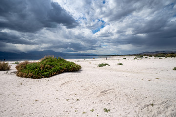 Sweeping, wide angle view of the decaying beach at the Salton Sea in California, as storm clouds roll in