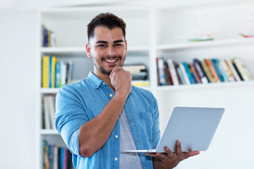 Laughing mexican hipster man with beard and computer