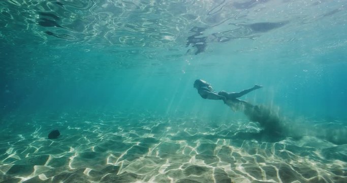Beautiful woman swimming in pristine blue ocean water