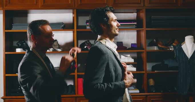 Slow motion of tailor taking a measures of handsome man for a new handmade great quality suit  in atelier.