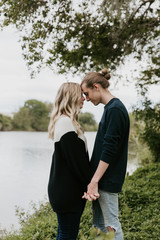 Fototapeta premium Young Romantic Couple Holding Each Other for Couples Portraits by the Pond Outside in Nature