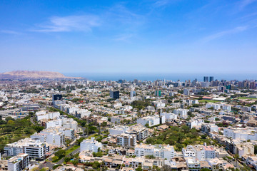 Fototapeta na wymiar Lima, Peru - March 12 2019: Aerial view of Miraflores district including La Aurora parks. Clear and bright day, travel and destinations concept. Drone aerial shot of Lima's cityscape.