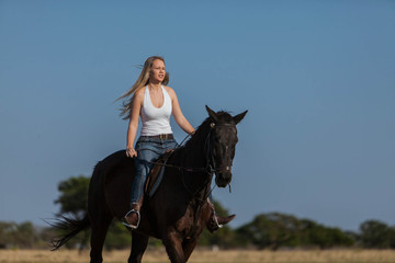 Fototapeta na wymiar A gorgeous blonde cowgirl riding horse