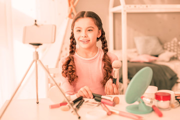 Obraz premium Delighted nice girl sitting in front of her smartphone