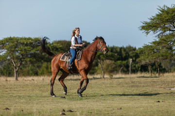 Attractive young blonde woman riding her horse