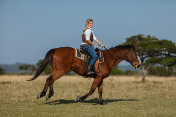 Attractive young blonde woman riding her horse