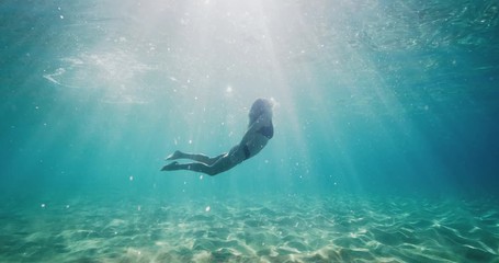 Underwater shot of beautiful woman swimming in ocean paradise