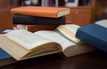 several open and closed books on wooden table