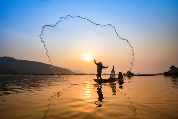 Asia fisherman net using on wooden boat casting net sunset or sunrise in the Mekong river - obrazy, fototapety, plakaty
