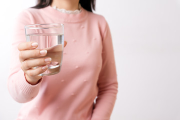 A glass of clean mineral water in woman's hands. Concept of environment protection, healthy drink and healthcare.