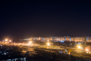 Fototapeta na wymiar Bright railway station at night against the backdrop of the outskirts of the city. Freight trains.