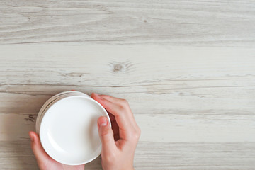Woman putting a white plate on the table.  テーブルの上に白い皿を置く女性