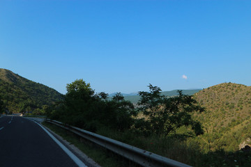 Road to vacation mountains, valley, green trees and blue sky