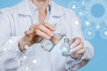 A laboratory assistant pouring some substance from a glass into a bottle.