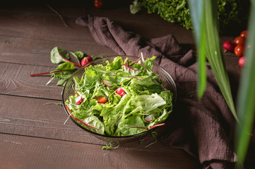 Full bowl of fresh green salad on dark background