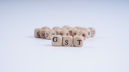 GST inscription on wooden alphabet over white background with selective focus