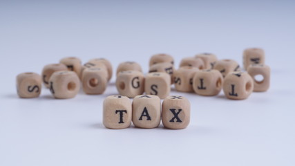 TAX inscription on wooden alphabet over white background with selective focus