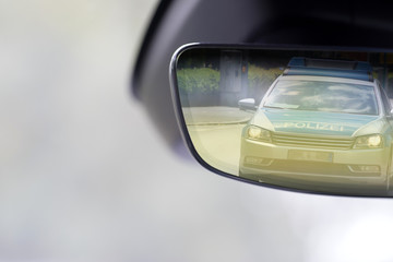 Innenraum von einem Fahrzeug und Polizeiauto im Rückspiegel