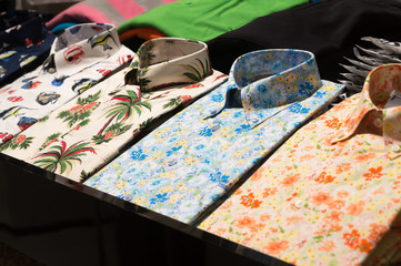 Folded shirts with colorful pattern in order on shelf are on sale in department store, colorful shirts are stacking in order on sale in a shop