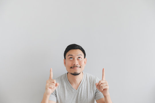 Happy face of man in grey t-shirt with hand point on empty space.