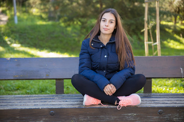 Obraz premium Content pretty sporty woman posing at camera on bench