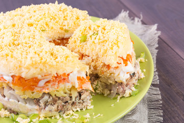 Mimosa canned fish salad layers in the shape of a circle with a portion. Angle view