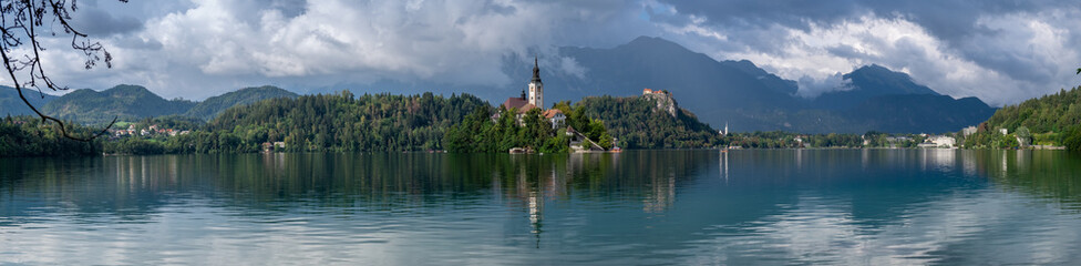Fototapeta na wymiar Very large panoramic view on The Church of Mary the Queen, located on an island in Lake Bled. Slovenia