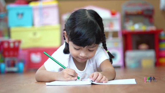 A cute child Asian girl doing homework and reading a book. Kid enjoy learning with happiness at home. Clever,Education and smart learning concept. (Video Slow motion).
