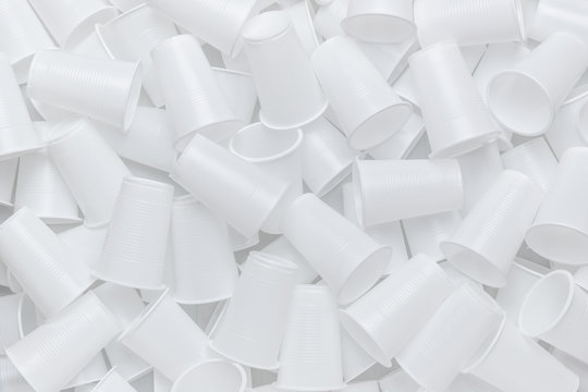 The texture of randomly scattered white disposable plastic cups. Abstract background of plastic dishes.