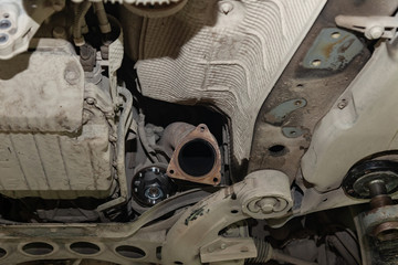 Close-up on the part of the bottom of the car from the front of the exhaust pipe and the catalyst disassembled during the repair in the workshop auto service vehicles