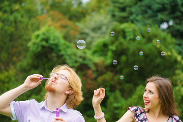 Couple blowing soap bubbles, having fun
