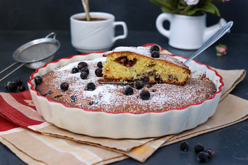 Black currant cake is located in a ceramic form with a cut piece of cake