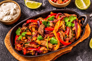 FAJITAS with colored pepper and onions, served with tortillas.