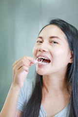 Asian woman using dental floss to cleaning her teeth at home.