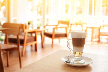 Cup of Hot  Latte Coffee on wood table with light window.
