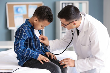 Pediatrician examining African-American boy in clinic