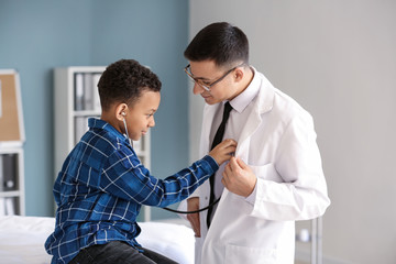 Fototapeta premium African-American boy playing with stethoscope at pediatrician's office